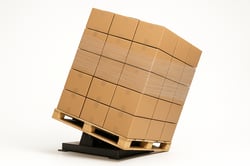 Photorealistic image on a clean white background of a pallet stability test in progress The pallet of neatly stacked boxes is positioned on a mechanical tilt platform angled slightly to simulate a tilt test Boxes remain securely in place with realist-1