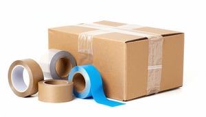 Rolls of paper tape and wateractivated tape beside a sealed cardboard box showing the ecofriendly sealing options clearly placed on a white background-1