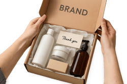 photographic Photorealistic image of hands opening a branded ecommerce box revealing neatly arranged products inside with tissue paper and a thankyou