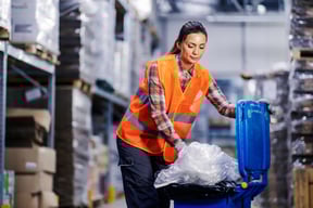 Warehouse Operative Placing Plastic Waste in a Wheelie Bin